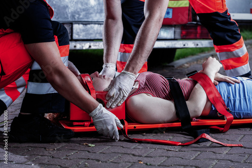 Canvas Print Professional medical rescuer bending over a car accident victim lying on a stret
