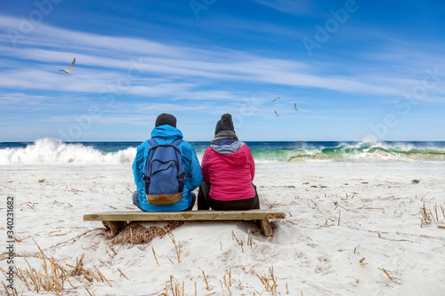 Paar sitzt verträumt am Strand und schaut auf die Wellen am Meer