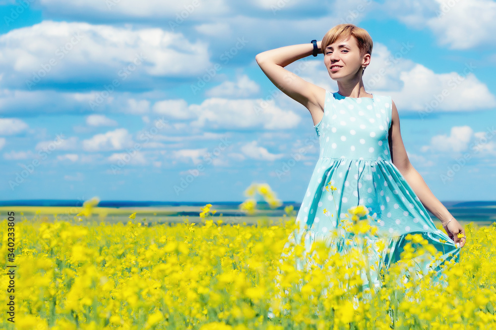 Fototapeta premium young beautiful red haired woman on a blooming rapeseed field