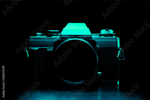 Vintage 35mm slr film camera silhouette in aqua-blue light. Silhouette of a 35mm film camera. photo