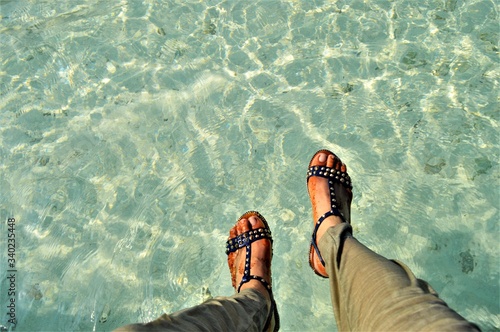 closeup image of woman feet in the beach of Maldives, Biyadhoo island, wearing sandal shoes
