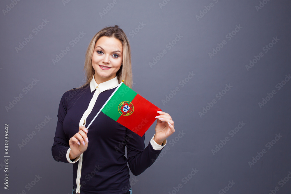 Immigration and the study of foreign languages, concept. A young smiling woman with a Portugal flag in her hand. Immigration and the study of foreign languages, concept. A young smiling woman with a Portugal flag in her hand.