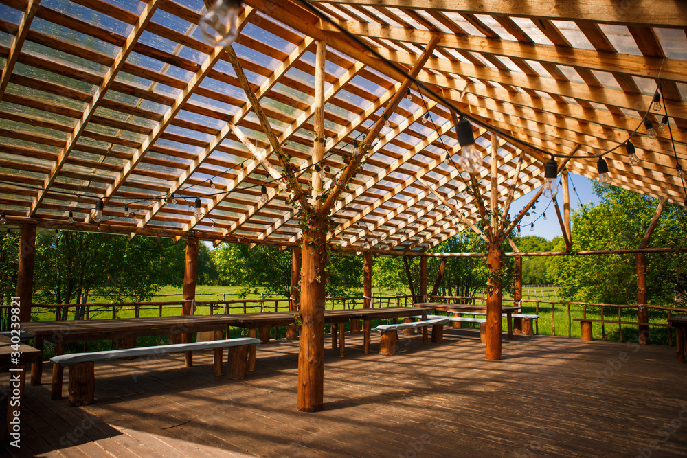 Wooden gazebo in nature in the Park for events and banquets. Sunlight through a grid of wooden beams-a game of chiaroscuro. Place for text and background Wooden gazebo in nature in the Park for events and banquets. Sunlight through a grid of wooden beams-a game of chiaroscuro. Place for text and background
