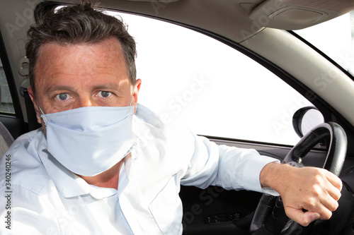 handsome blue eyes man protect in Medical Mask driving car during coronavirus covid-19 quarantine