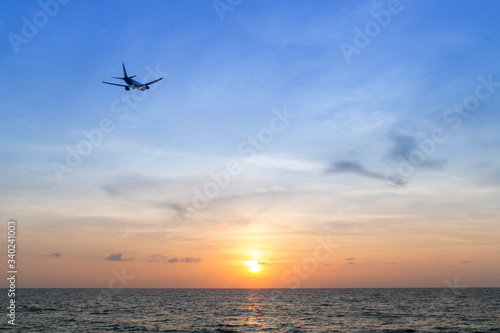 airplane at sunset flying over ocean