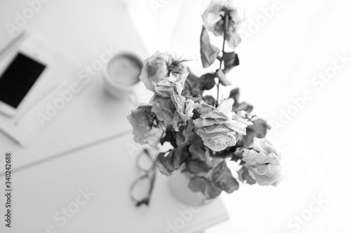 vintage style - glasses, note book with pencil pen and coffee mug on the table.old roses at the working table as procrastination or delay concept. Black and white image