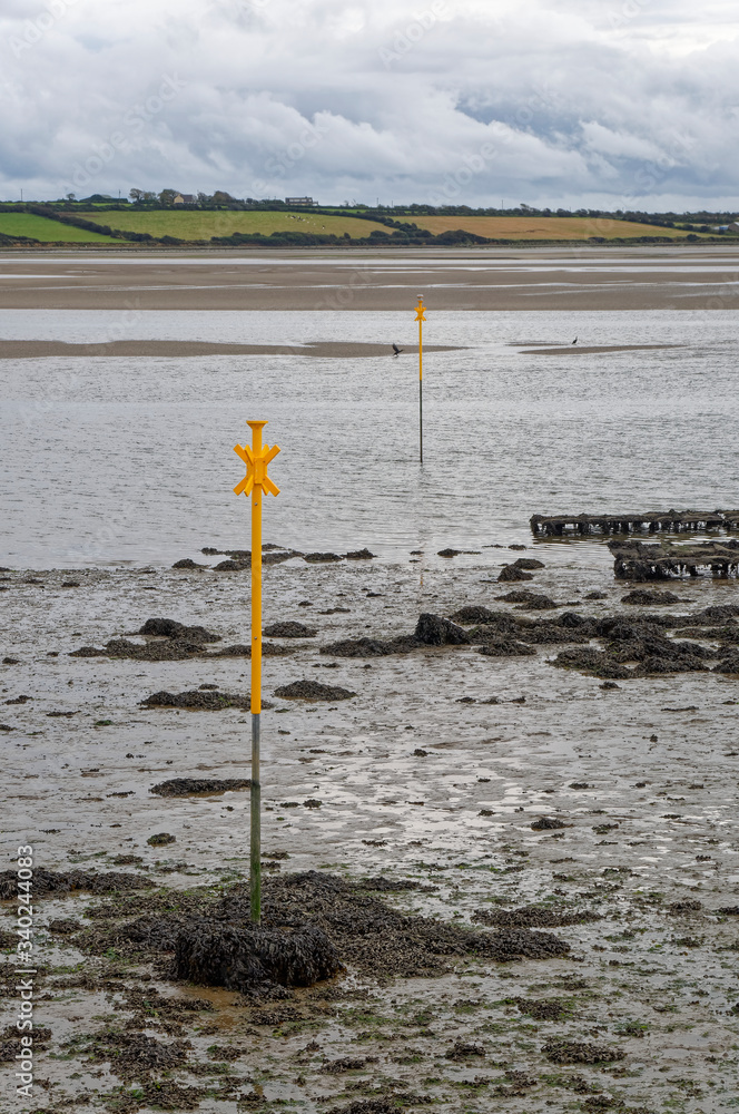 Freshly painted yellow Navigation Marks in the Estuary at low tide at St Kieran's Quay in County Wexford.