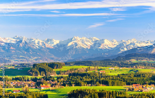Allgäu landscape with snowy mountains and green meadows in spring. Bavaria, Germany