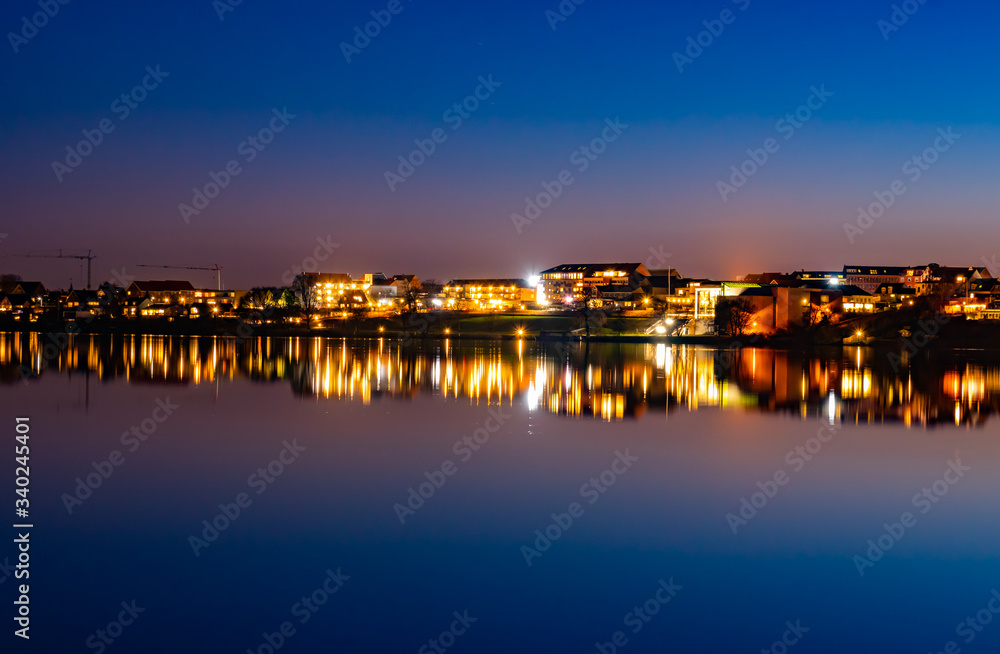 A beutiful water reflection of the city of Skanderborg in Denmark by night at a lake