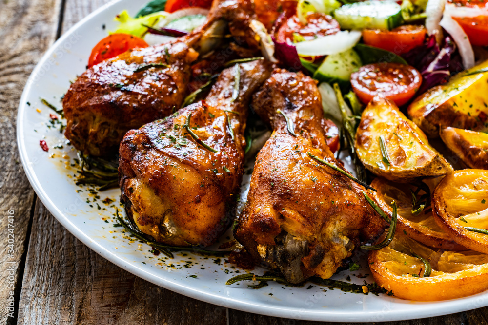 Barbecue chicken drumsticks with vegetables on wooden table Barbecue chicken drumsticks with vegetables on wooden table