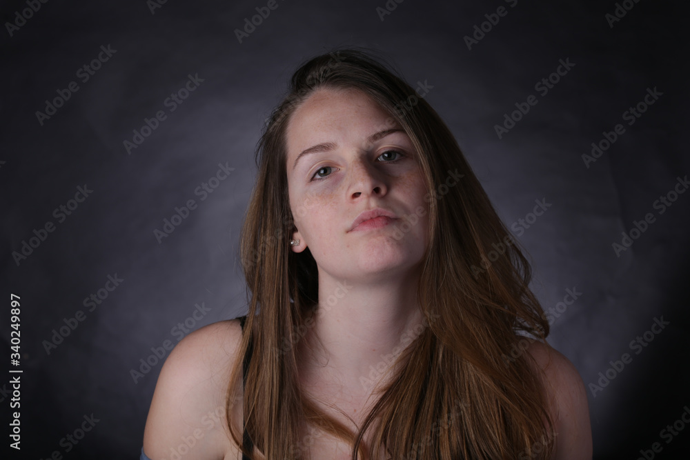 Studio portrait of young girl with light hair and freckles, with dark background. Studio portrait of young girl with light hair and freckles, with dark background.