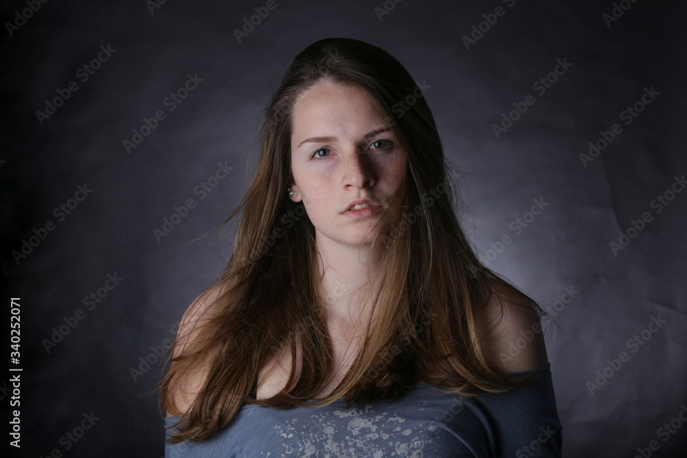 Studio portrait of young girl with light hair and freckles, with dark background. Studio portrait of young girl with light hair and freckles, with dark background.