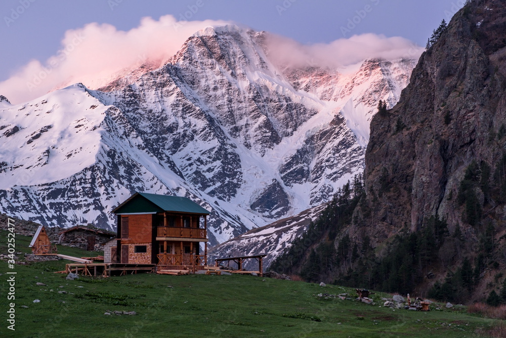 House in the mountains. Elbrus region. In the background, the glacier in the form of the number seven.