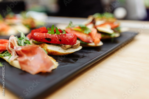 Tasty italian appetizer bruschettes with tomatoes anchovies prosciutto, mozarella, shrimps and seafood