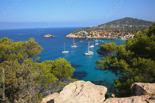 View from the South coast of Ibiza showing boats anchored in the bay. Beautiful landscape with cliffs & turquoise water. Baleric Islands, Spain.