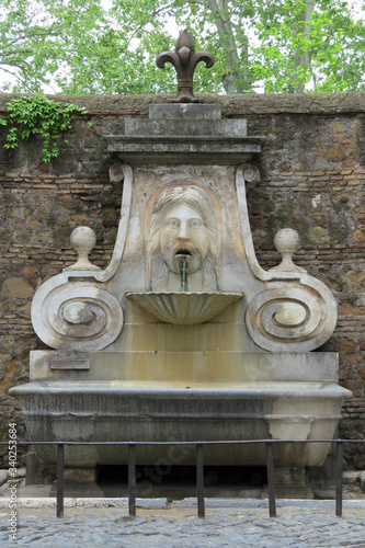 Close-up public water shooting drinking fountain ("nasone") with the image of a head; Rome, Italy, Europe
