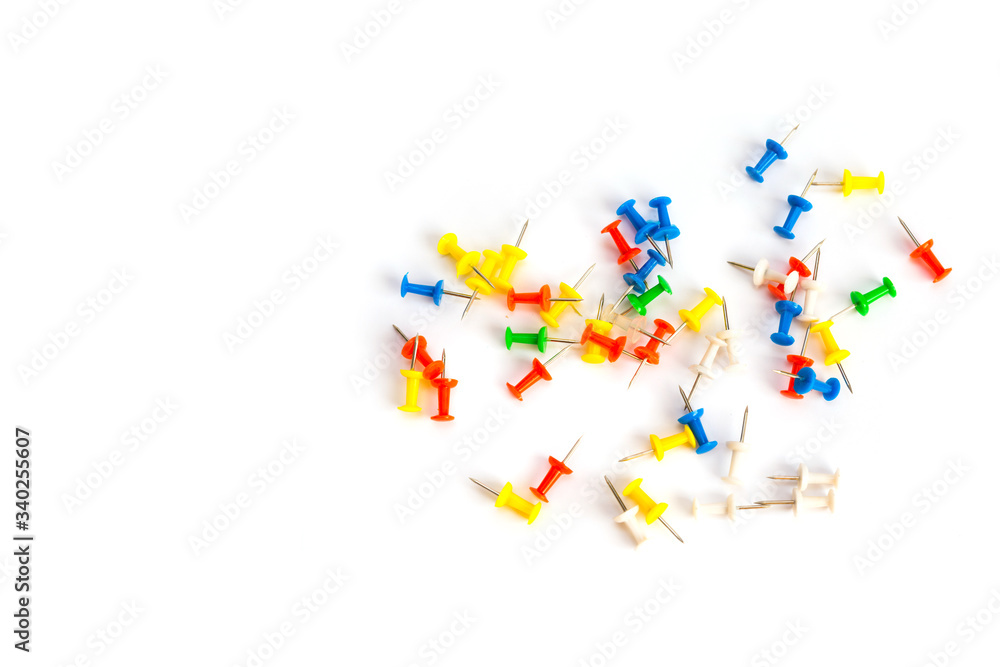 Multi-colored pushpins scattered over a white background.