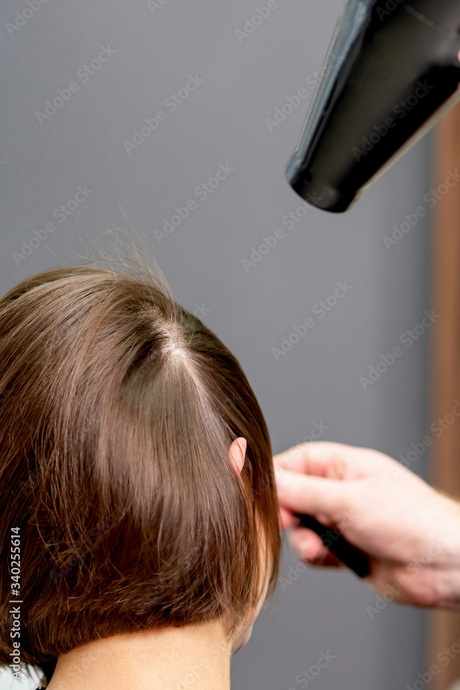 Fototapeta premium Hairstylist dries hair of woman.