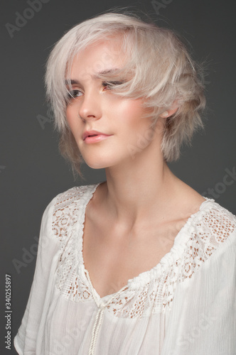 Calm beautiful blonde in a white blouse. On a dark gray background