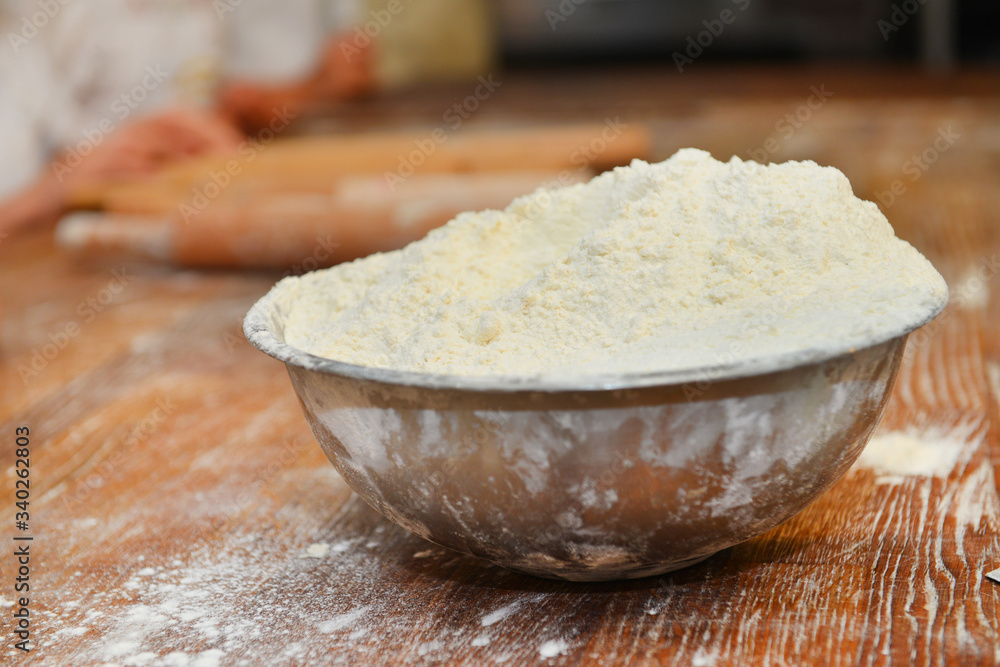 wheat flour is in an iron plate on a wooden table wheat flour is in an iron plate on a wooden table