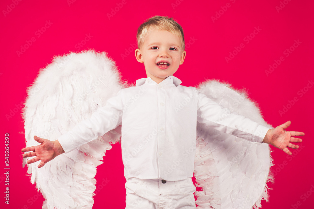 Beautiful little angel boy. Small cupid isolated on a red background. Cute little boy with white wings. Beautiful little angel boy. Small cupid isolated on a red background. Cute little boy with white wings.