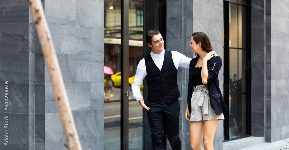 Business colleagues couple walking on street while talking to each other. Young happy business couple walking outdoor office building