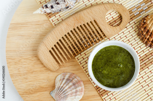 Diy green mask (scrub) with spirulina extract and wooden hair brush. Ingredients for preparing homemade cosmetics. Natural beauty treatment recipe and zero waste concept. Top view, copy space.