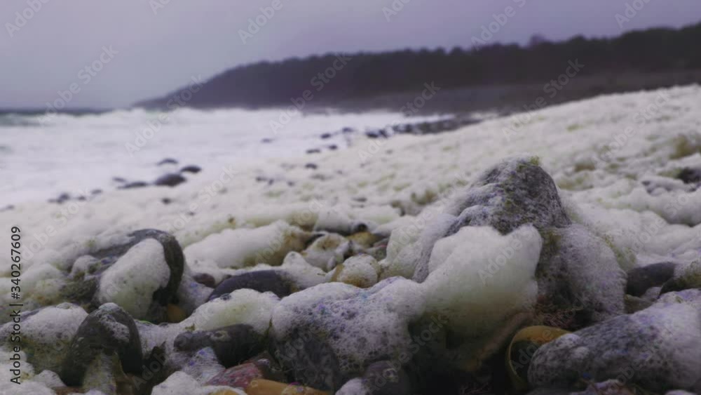 Dirty Yellow Foam Or Bubbles Left On The Rocky Shore, Thrown By The Strong Waves On Skagerak Coast In Arendal, Norway. - closeup shot Dirty Yellow Foam Or Bubbles Left On The Rocky Shore, Thrown By The Strong Waves On Skagerak Coast In Arendal, Norway. - closeup shot