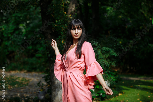 young woman in pink dress spinning in the garden