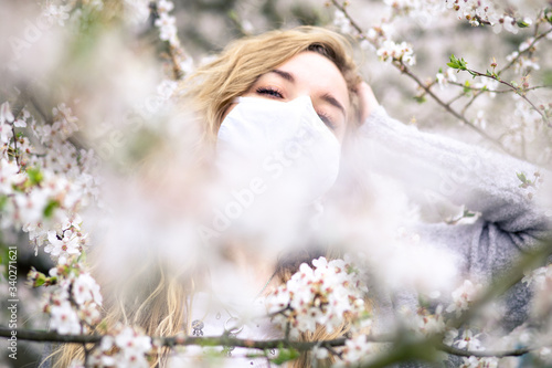 
girl in white medical mask and spring blossom