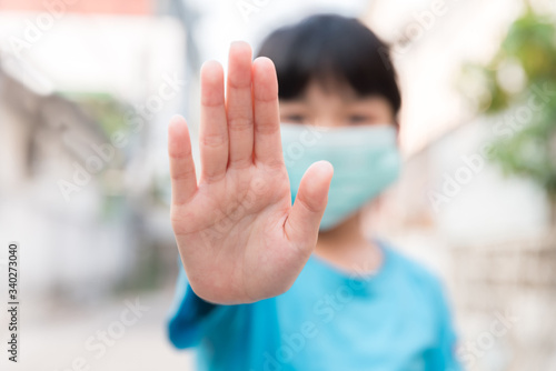 Asian Child girl wear medical face mask during pandemic Coronavirus Covid-19 outbreak and show stop hands gesture for stop corona virus outbreak ,stay at home to quarantine motivational phrase © Sakan