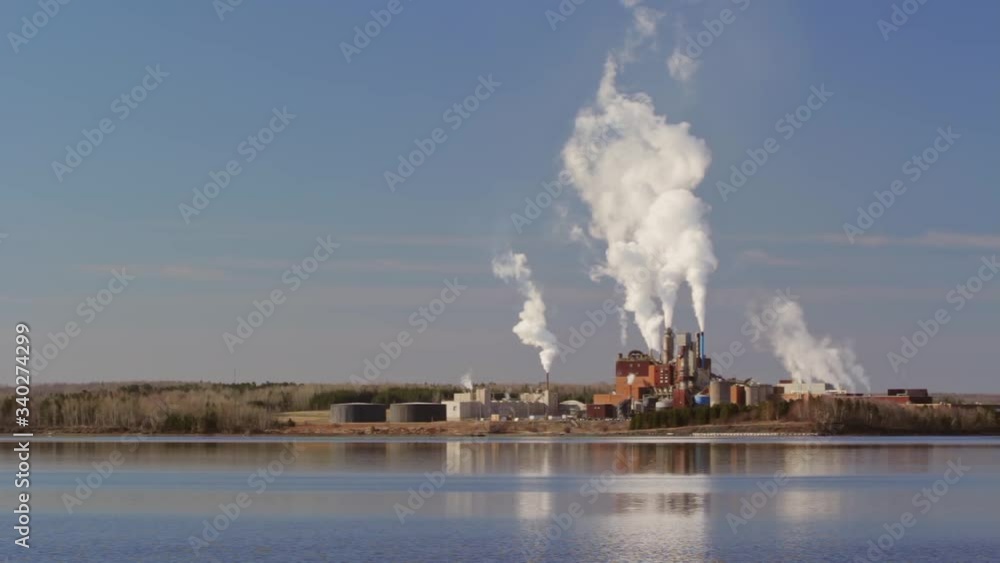 Industrial plant spewing emissions beside large body of water Industrial plant spewing emissions beside large body of water