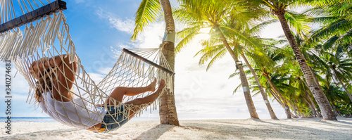 Woman relaxing on hammock on the beach. Travel and vacation concept. Banner edition.