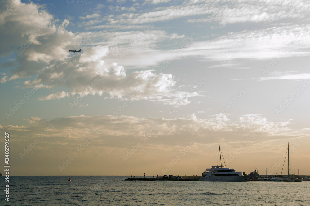 

Sunset over the seaport of Paphos in Cyprus with a flying airplane