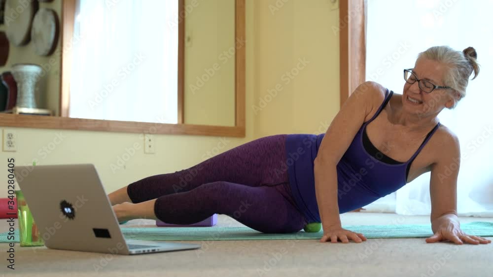 Mature woman in pain while doing myofascial deep tissue massage and looking at her therapist on the computer screen. Mature woman in pain while doing myofascial deep tissue massage and looking at her therapist on the computer screen.