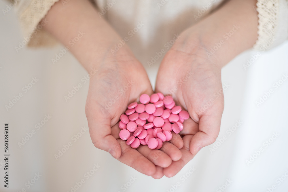 children's hands hold pink pills, protection and care, health and charity, vitamins and supplements