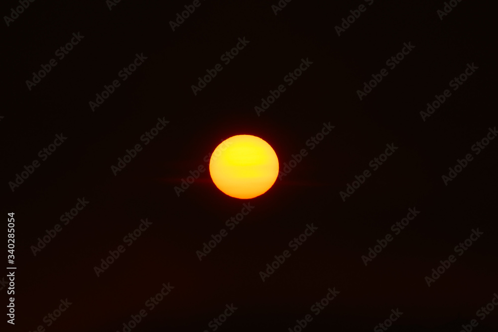 Orange sun in the dark sunset sky