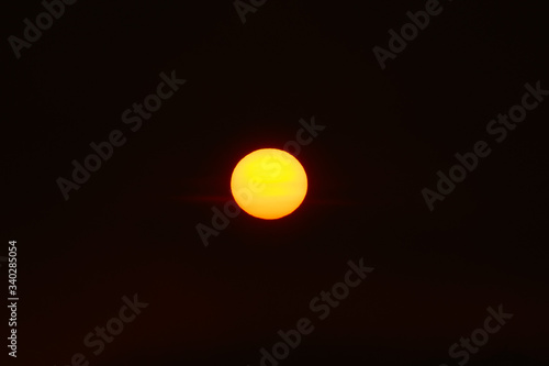 Orange sun in the dark sunset sky