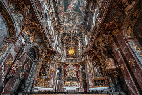 Ultrawide upward view of ceiling fresco altar facade inside Baroque style church Asamkirche in Munich, Germany