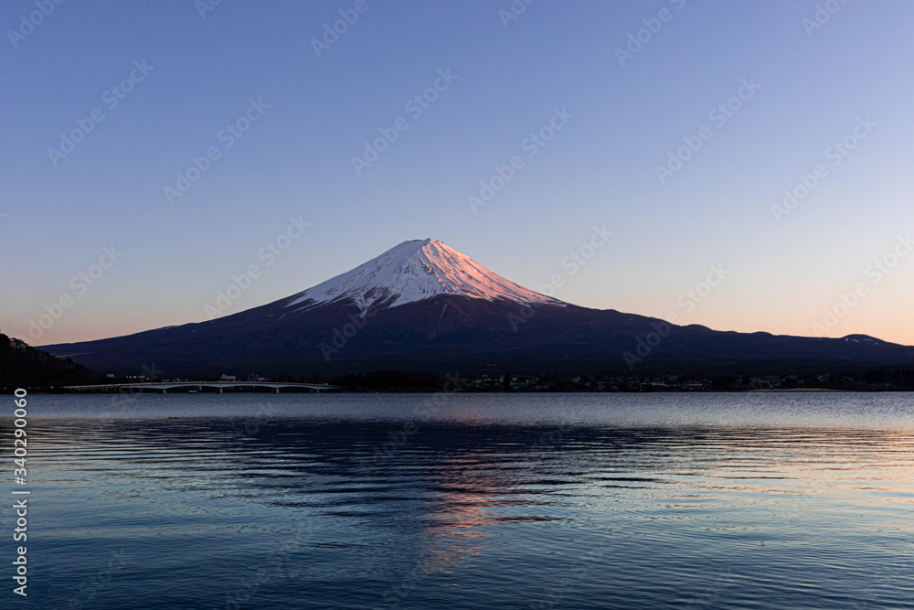 湖面に映り込む夕日に照らされた富士山
