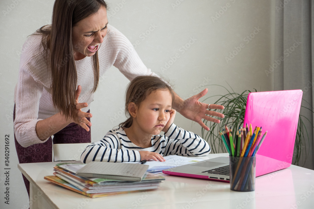 Fototapeta premium Furious adult woman screaming at daughter while she helping to do her homework assignment at home