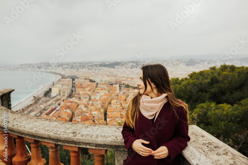 Young female traveler enjoying great view on the Nice city, France. Beautiful panoramic aerial cityscape top view of Nice, of French riviera. Landscape of harbor, town of Cote d'Azur France.Copy space