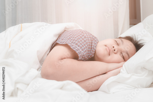 cute obese asian boy sleep on bed in the bedroom.
