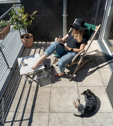Blonde woman and and puppy enjoying a sunny day on balcony