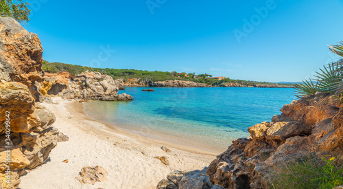 Blue sky over rocks and sand in Alghero shore