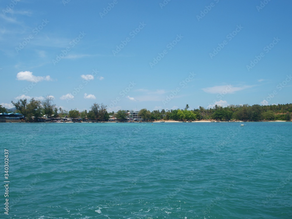 Panoramic view from sea to the land. Blue sky and rare white small clouds. Sandy shore, green forest and coast line on the horizon. Tropical paradise and turquoise transparent water. Landscape, beach.