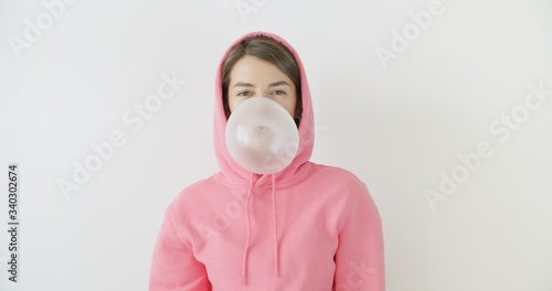 girl dressed in pink hoodie blowing bubblegum