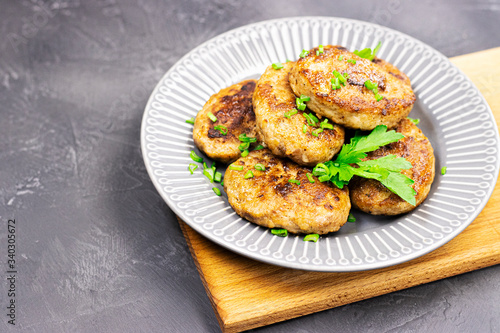 fresh meat fried cutlets with greens on a plate, close-up. brutal men's food on a wooden stand on a black stone table