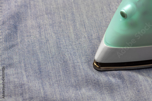 Ironing of blue denim fabric closeup.