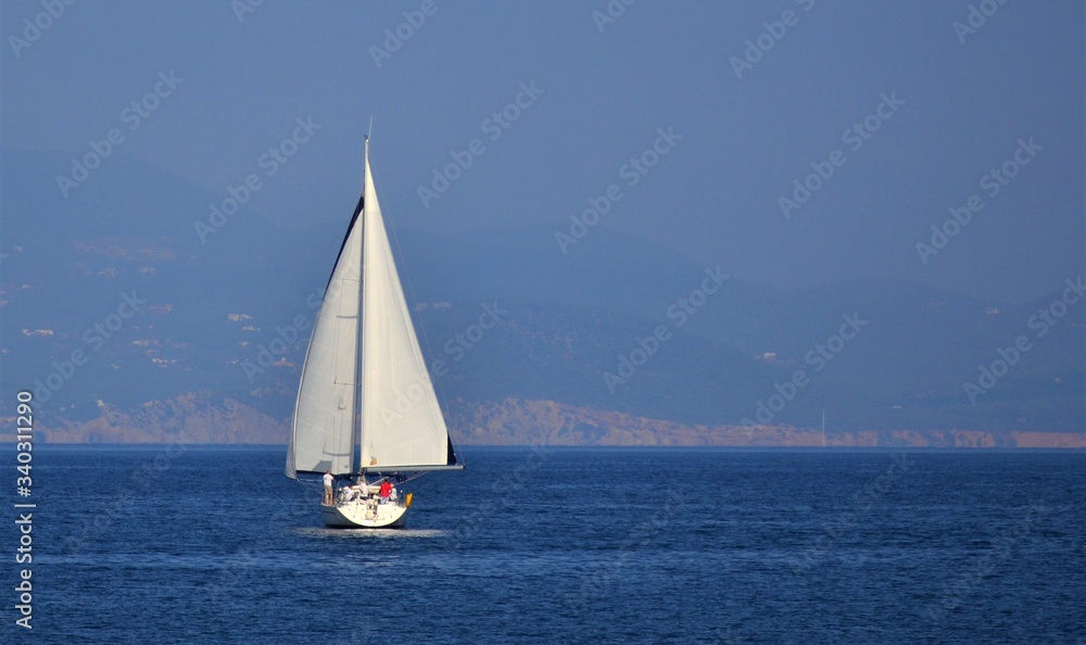 white sailboat with people on the high seas